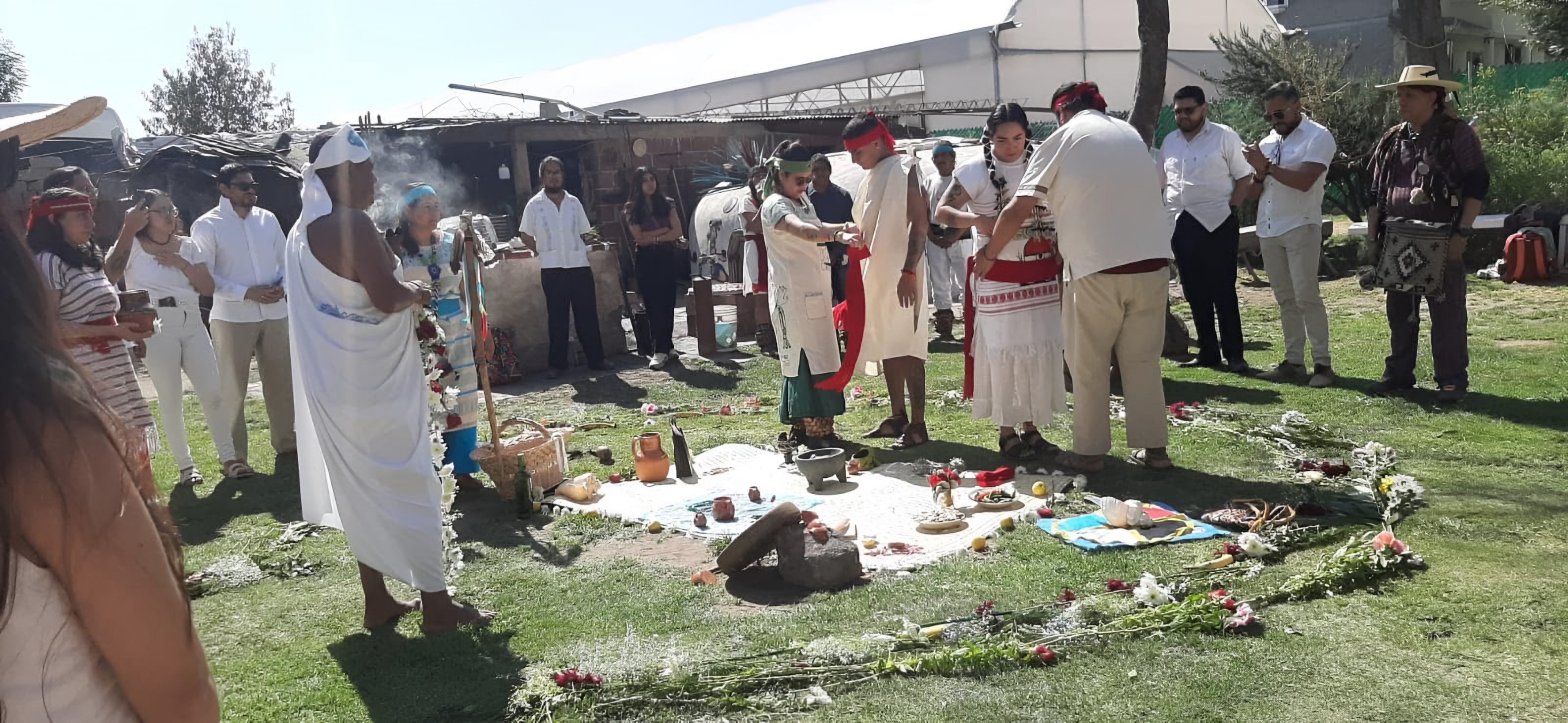 Ceremonia al aire libre con una ofrenda de flores y frutos en el centro del círculo