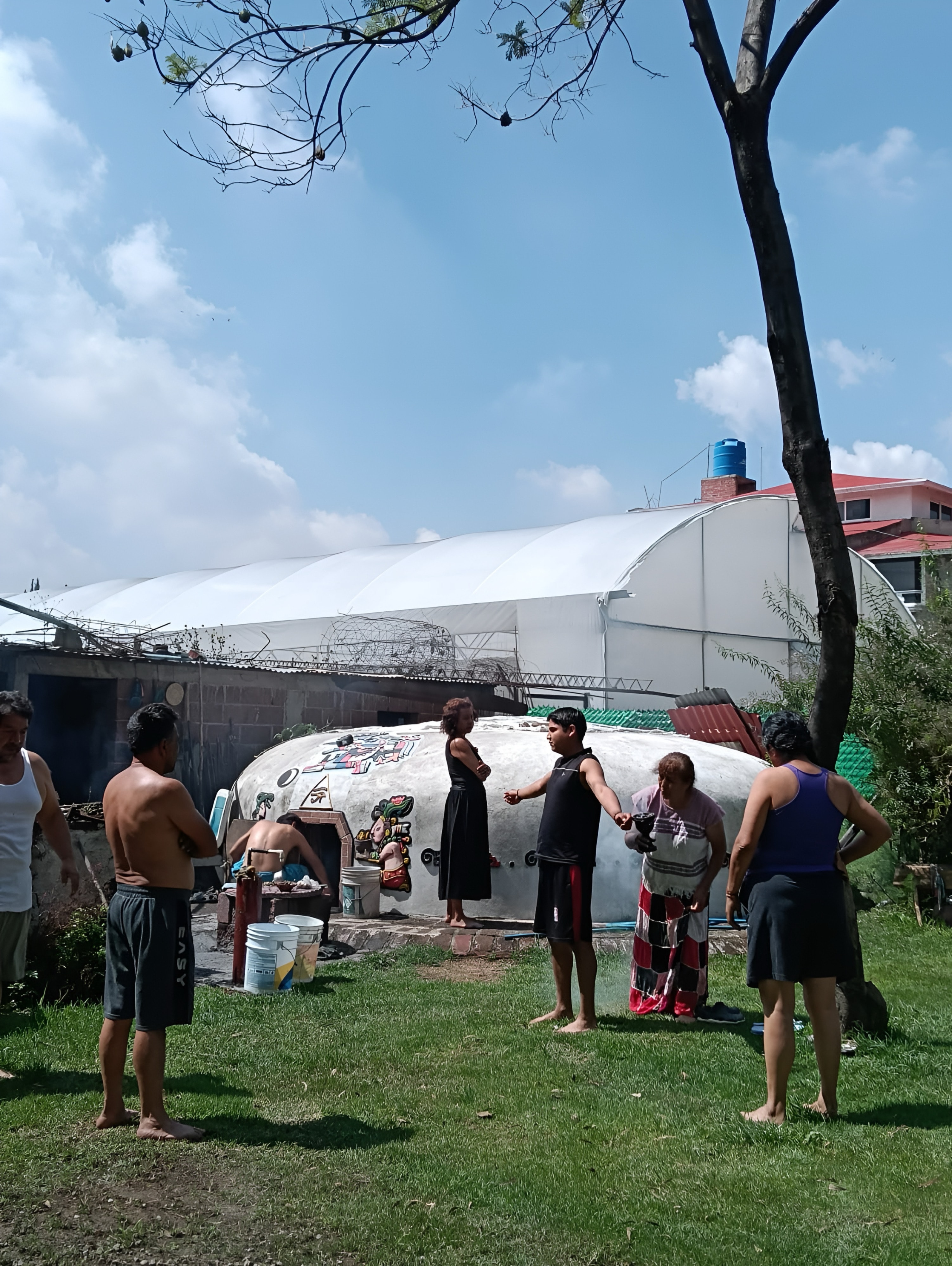 Grupo de personas en el jardín junto al domo del temazcal, antes de entrar a la ceremonia
