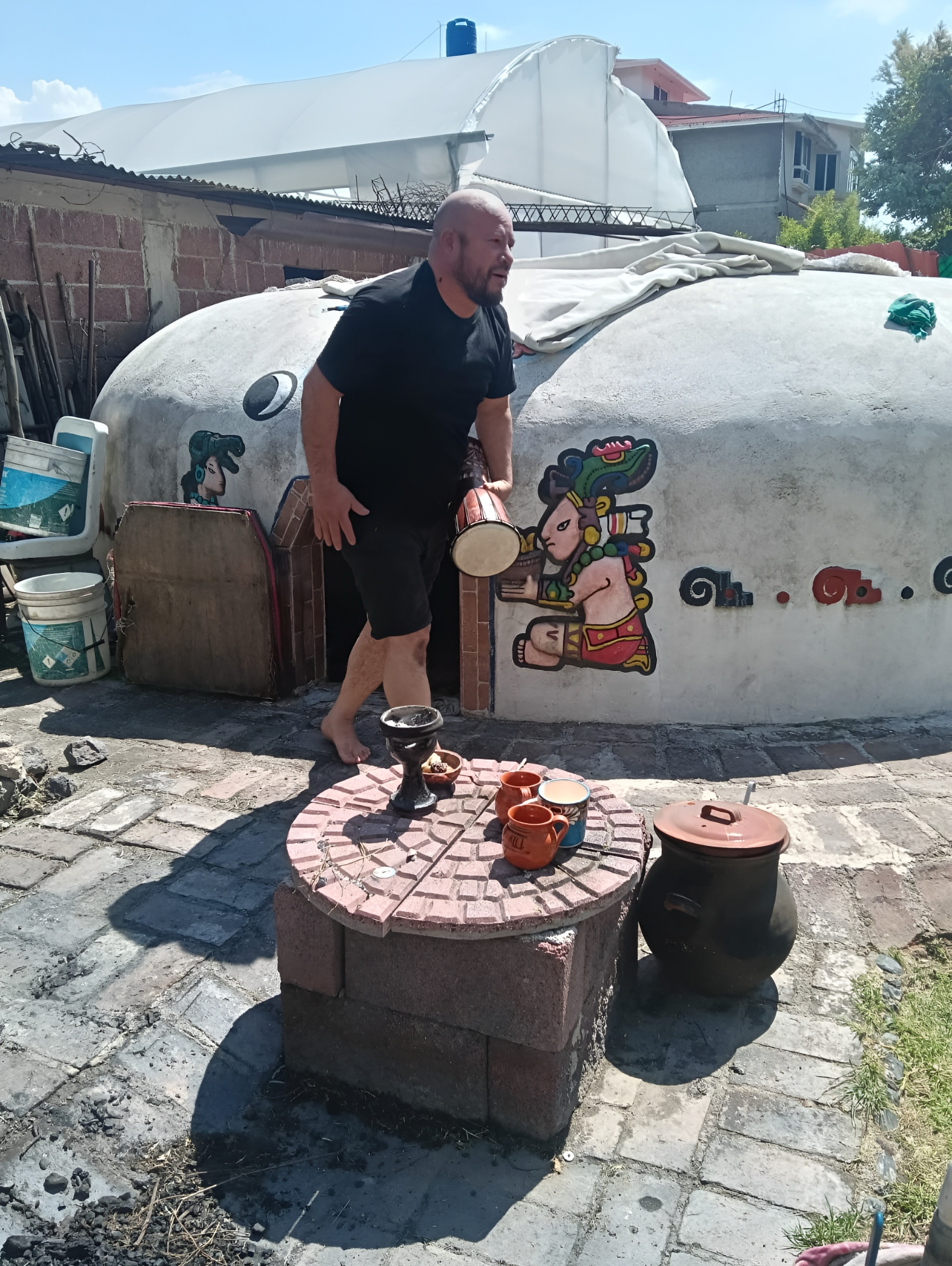 El temazcalero con el tambor junto a la entrada del temazcal